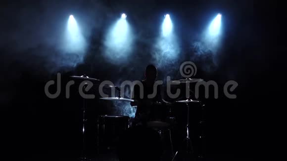 精力充沛的音乐家在鼓上演奏好音乐黑色烟熏背景背光剪影慢动作视频的预览图