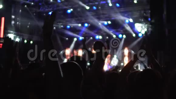 歌迷们在灯火通明的音乐厅挥舞双手跳舞的剪影视频的预览图