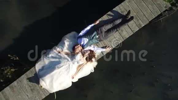 新娘躺在公园的一座小桥上顶部的空中景观拍摄一个dron相机就会飞走视频的预览图
