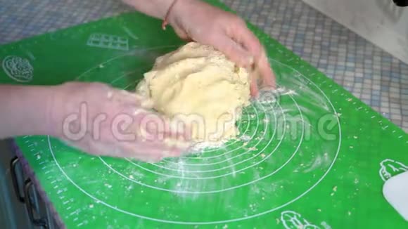 特写镜头一位老年妇女的双手小心地将烘焙面团混合在厨房餐桌上视频的预览图