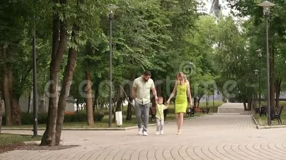 快乐的爸爸和妈妈和小儿子在夏天公园散步视频的预览图