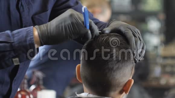戴着黑手套的理发师在一个亚洲孩子的头上剃了一个离别背面观看60fps视频的预览图