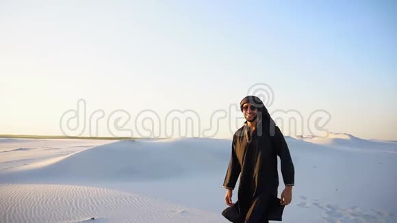 在晴朗温暖的夜晚坎杜尔自信的男性英俊的阿拉伯人在白色沙漠中散步视频的预览图