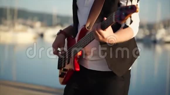 一位音乐家白天在街上演奏的低音吉他特写镜头视频的预览图