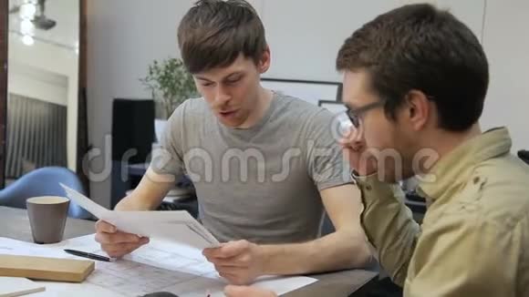 两位建筑师看着室内平面图坐在办公室室内交谈视频的预览图