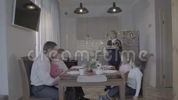 快乐的洛夫利四个孩子一家人在厨房餐桌上庆祝除夕父亲儿子女儿笑着母亲在服侍着视频的预览图