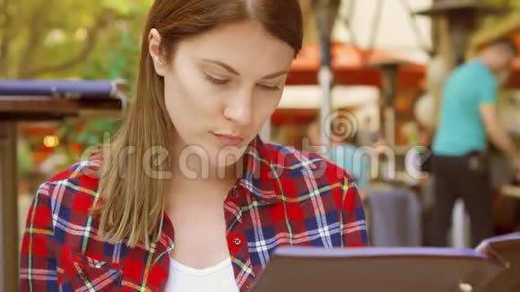 饥饿的女人坐在咖啡馆里看菜单微笑着美丽的女性选择餐厅的食物视频的预览图