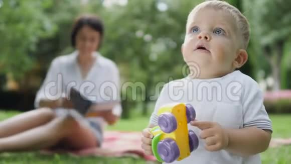 男孩玩玩具妈妈在模糊的背景下看书视频的预览图