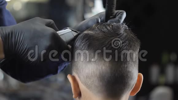 戴着黑手套的理发师在一个亚洲孩子的头上剃掉了一个离别背面观看60fps视频的预览图