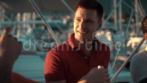 微笑的年轻人在游艇上倾听朋友的声音视频的预览图