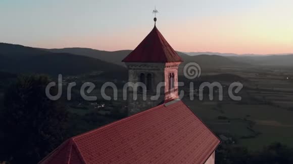 在日落时分在山上环绕着古老的天主教教堂美丽的乡村景色视频的预览图