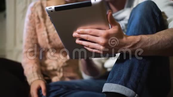 年轻人在圣诞节的平板电脑上给他的女朋友看东西视频的预览图