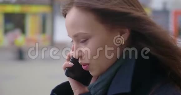 漂亮开朗的年轻女人在外面用手机她在电话里说着笑拥挤的城市视频的预览图