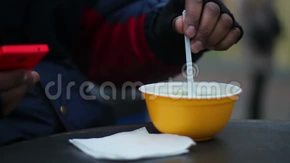 在寒冷的刮风天气里有需要的人在户外吃热汤体力劳动者的午餐视频的预览图