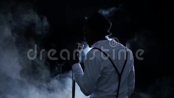美国黑人男音乐家从后面的烟雾中看到在录音室唱歌黑色背景视频的预览图