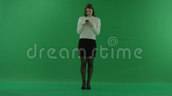 女孩站直在绿色屏幕上的电话旁聊天视频的预览图