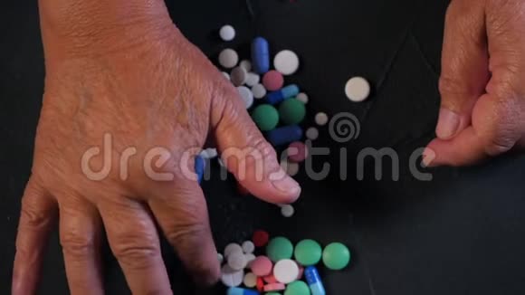 祖母在家里的黑桌上数着五颜六色的药片老年概念药物治疗最后报告视频的预览图