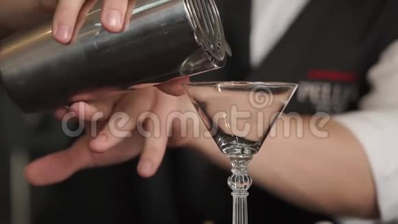 酒保正在酒吧里把红色的酒精鸡尾酒从摇床倒入玻璃杯视频的预览图