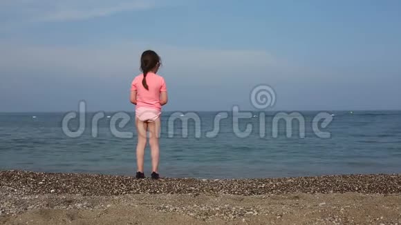 美丽的女孩把石头扔进海里视频的预览图