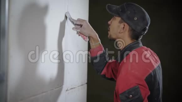 收缩工人正在用铲刀在平面上铲平墙壁视频的预览图