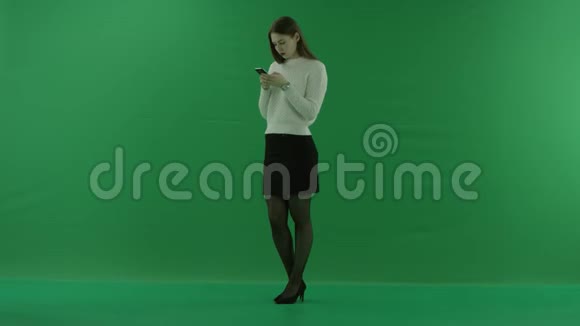女孩站在半个转弯处看着左边在绿色的屏幕上通过电话聊天视频的预览图