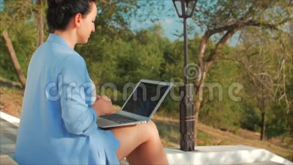 商务女士在笔记本电脑上工作漂亮的黑发女郎穿着蓝色西装带着笔记本电脑漂亮的女人在她的电脑上工作视频的预览图