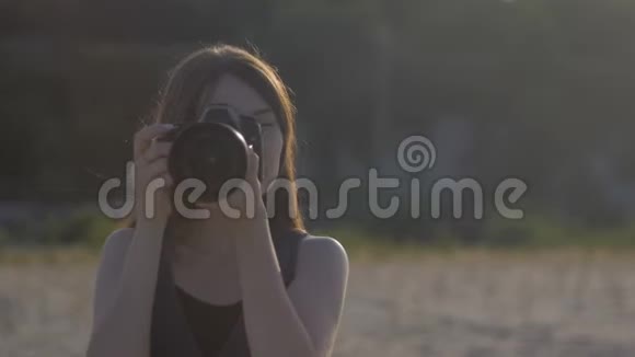 年轻漂亮的女摄影师带着专业的相机我们的门女孩正在拍一张照片看着照片视频的预览图