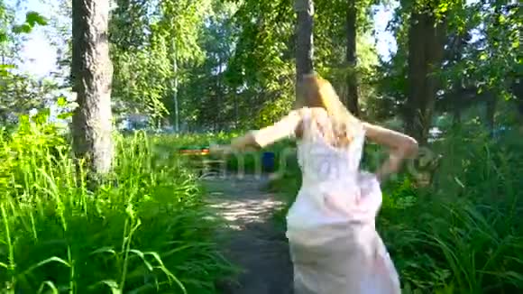 穿裙子的女孩穿过公园坐在石头上视频的预览图