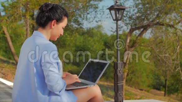 商务女士在笔记本电脑上工作漂亮的黑发女郎穿着蓝色西装带着笔记本电脑漂亮的女人在她的电脑上工作视频的预览图