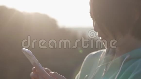 这位年轻的亚洲女孩在阳光下通过手机聊天一头黑发的特写照片户外概念视频的预览图