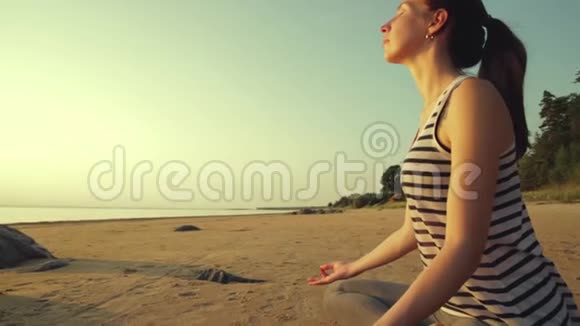 女人在莲花的位置在海滩上沉思日落时美丽的海滩视频的预览图