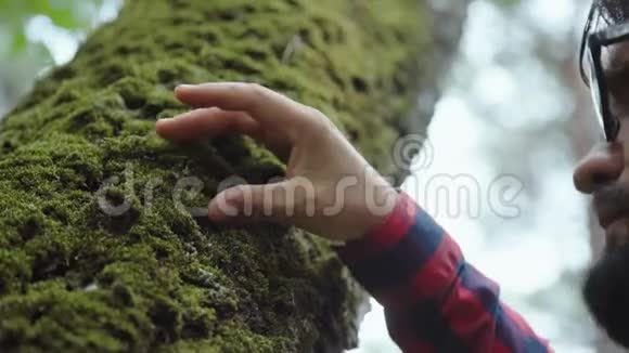 戴眼镜的现代生态学家从一棵树上采集苔藓样本视频的预览图