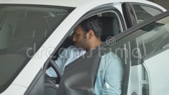 一个男人坐在开着车门的车里的画像视频的预览图