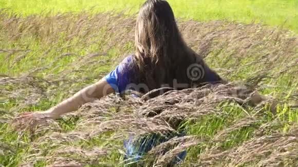 女孩走在绿草地上触摸植物视频的预览图