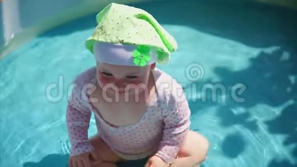 一个在游泳池里的小而有趣的婴儿用双手捂住脸视频的预览图