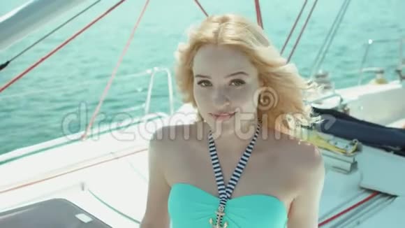 身穿比基尼的金发女郎坐在游艇上微笑着摆姿势视频的预览图