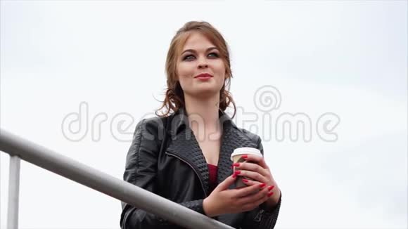 可爱的女人带着红色的头发带着咖啡在秋日的外卖中微笑视频的预览图