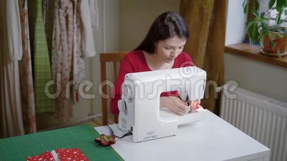 时装设计师每天在她的家庭作坊里缝纫用缝纫机缝制衣服衣服挂在衣架上视频的预览图