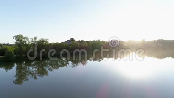 日出时美丽的自然明亮的阳光下绿树之间清澈的湖水视频的预览图