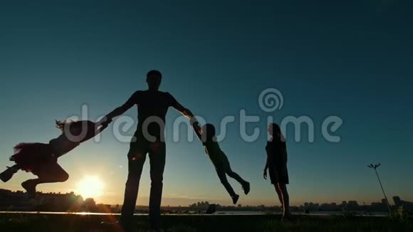 日落时的家庭幸福剪影父亲和孩子们玩慢动作视频的预览图