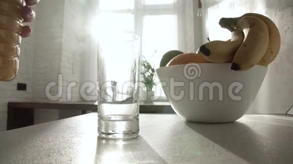 早餐将果汁倒入桌上的玻璃杯中视频的预览图