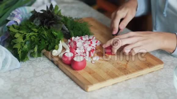 在木板上用刀切萝卜把女人的手收起来概念蔬菜视频的预览图