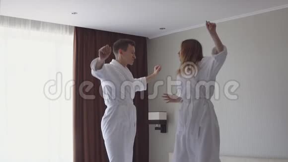 到达酒店后年轻夫妇在床上跳跃和跳舞的慢动作视频视频的预览图