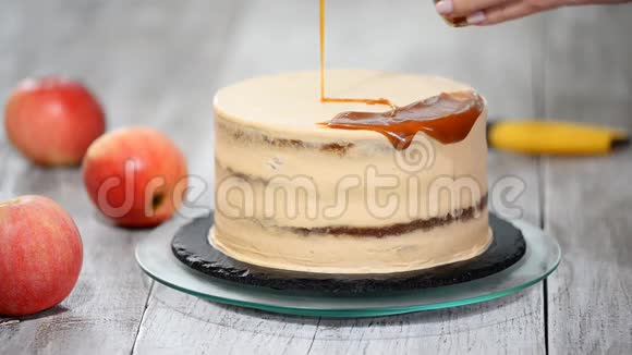 年轻女子把焦糖酱涂在美味的自制蛋糕上带苹果和鲜奶油的美味蛋糕视频的预览图