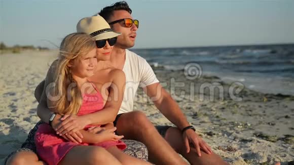 幸福的家庭和一个女儿在海滩度假微笑的父母在太阳镜与孩子享受日落视频的预览图