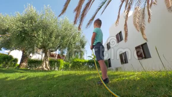孩子在用水管浇草坪时玩得开心视频的预览图