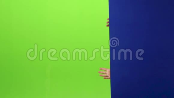 戴眼镜的小男孩出现在黑板的一侧双手握在绿色的屏幕上慢动作视频的预览图