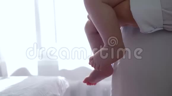 婴儿双脚特写女性双手抱着孩子在白色背景背光上的手臂视频的预览图
