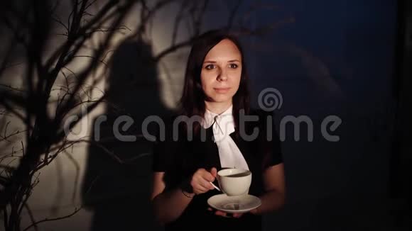 女人在黑暗的地方喝咖啡年轻的梦幻女子一边喝咖啡一边站在光线下视频的预览图