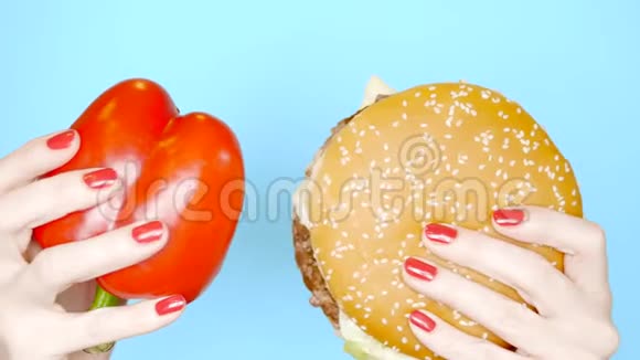 健康和不健康食品的概念甜红胡椒在明亮的蓝色背景上与汉堡包女性手视频的预览图